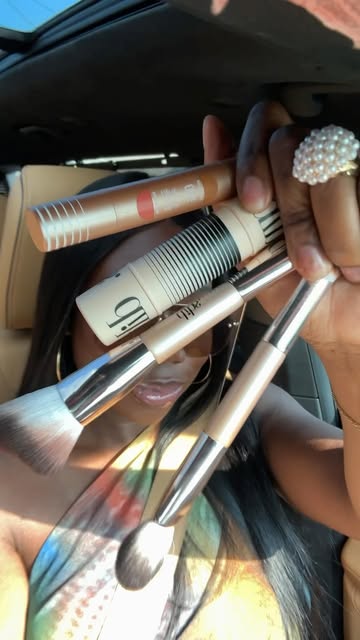 Mara holding a selection of makeup products and brushes